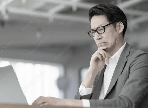 PCの前に悩んでいる男性の画像